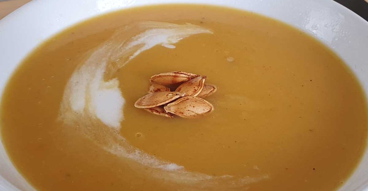 A bowl of pumpkin soup decorated with pumpkin seeds